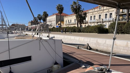 Voilier amarré au port de Sète avec architecture méditerranéenne et palmiers, vue littorale depuis l'appartement Ipanema