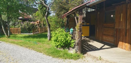 Extérieur du chalet en bois aux Gîtes les Grandes voies au Ménil avec jardins verdoyants et allée gravillonnée