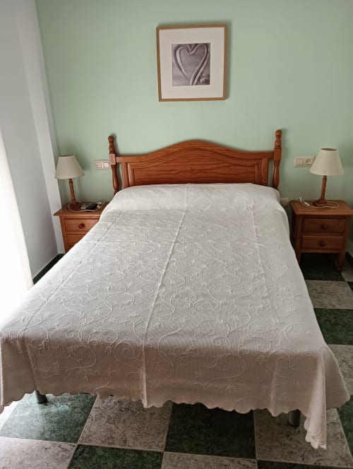 Double bedroom at Hostal San Andres in Carboneras with wooden bed, white bedspread, nightstands, lamps, and mint green walls