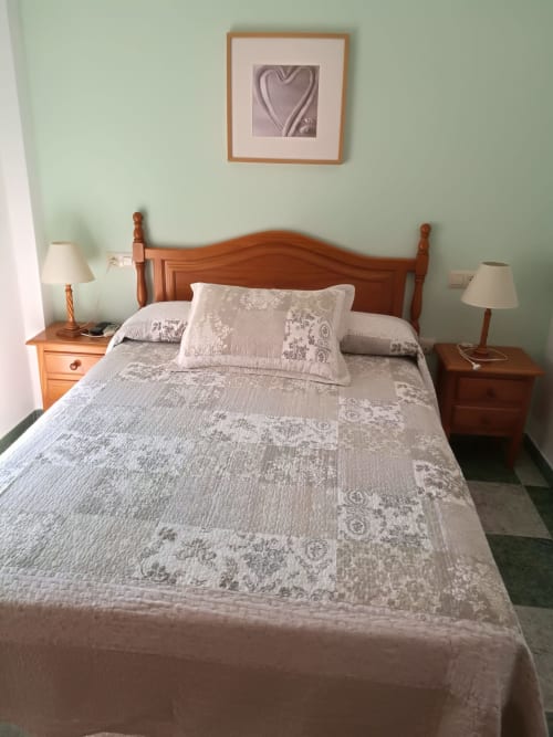 Cozy double bedroom at Hostal San Andres in Carboneras with wooden bed, patterned bedding, and mint green walls