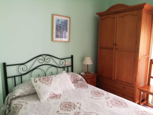 Double bedroom at Hostal San Andres in Carboneras with wrought iron bed, wooden wardrobe, and mint green walls