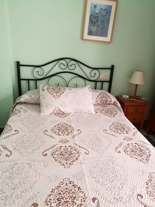 Double bed with burgundy damask bedding at Hostal San Andres in Carboneras, mint green walls, wrought iron headboard,