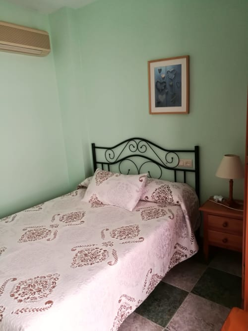 Cozy double bedroom at Hostal San Andres in Carboneras with mint walls, iron bed frame, and pink patterned bedding