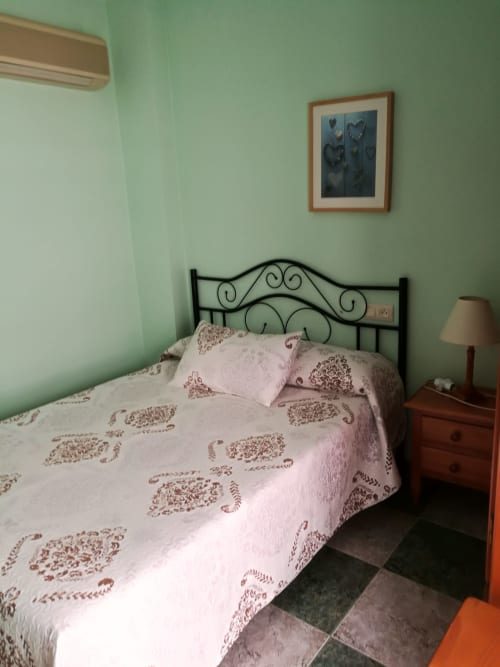 Cozy double bedroom at Hostal San Andres in Carboneras with wrought iron bed, mint green walls, and wooden nightstand