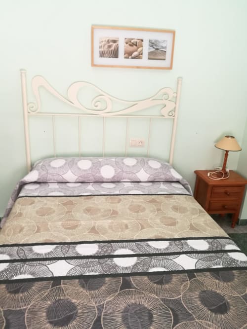 Cozy double bedroom at Hostal San Andres in Carboneras with white metal bed frame and patterned bedding