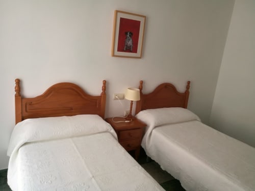 Twin beds with wooden headboards in a bright room at Hostal San Andres, Carboneras