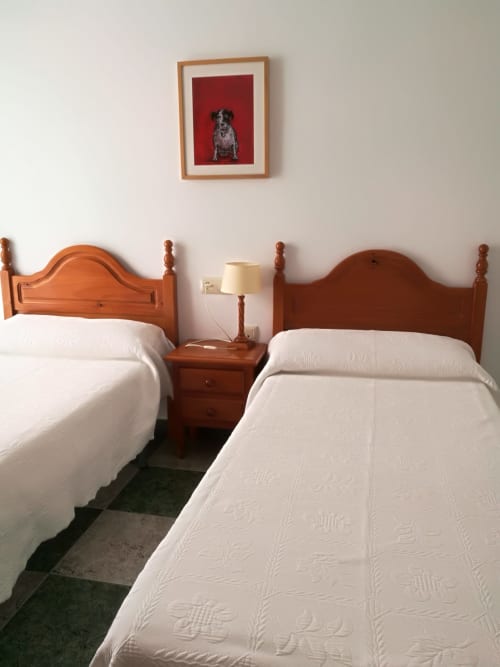 Two twin beds with white linens in a double room at Hostal San Andres, Carboneras, with wooden frames and nightstand lamp