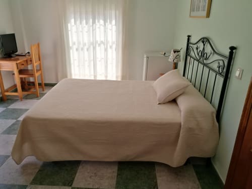 Bright double bedroom at Hostal San Andres in Carboneras with wrought iron bed and natural light