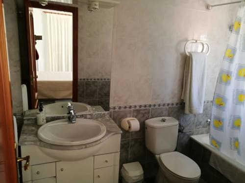 Bathroom at Hostal San Andres in Carboneras with sink, toilet, bathtub and yellow duck shower curtain