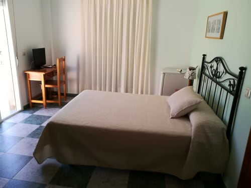 Bright double bedroom at Hostal San Andres Carboneras with wrought iron bed, wood desk, and terrace access