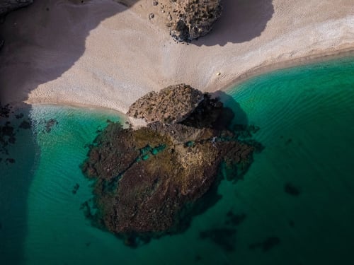 Aerial view of Carboneras beach with turquoise waters, white sand, and rocky outcrops near Hostal San Andres