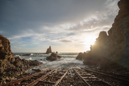Dramatic rocky coastline at Carboneras with shipwreck timbers, towering sea stacks, and waves at sunset near Hostal San