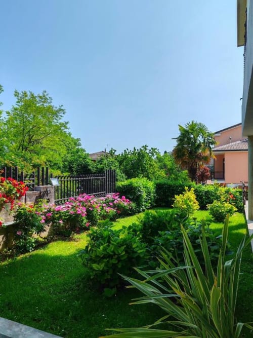 Giardino lussureggiante di Villa Andreina B&B ad Amandola, con fiori rosa, prato verde e casa in terracotta