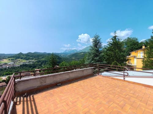 Terrazza di Villa Andreina a Sarnano con vista panoramica sulla valle, edificio giallo e Monti Sibillini.