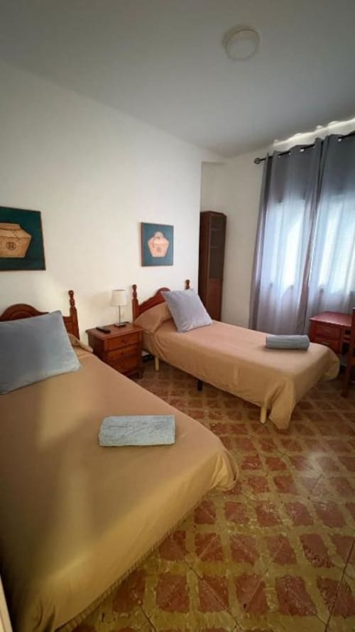 Helles Schlafzimmer mit zwei Einzelbetten, Holznachttischen und transparenten Vorhängen in einer Wohnung in Santa Cruz de Tenerife