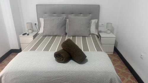 Modernes Schlafzimmer im Vive La Vacacional Apartment in Santa Cruz de Tenerife mit grauem Polsterkopfteil und gestreifter Bettwäsche