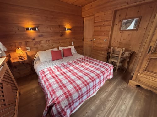 Cozy wood-paneled bedroom in Chalet Marie Claire with queen bed, red plaid duvet, and warm lighting at Chez Francine, Notre
