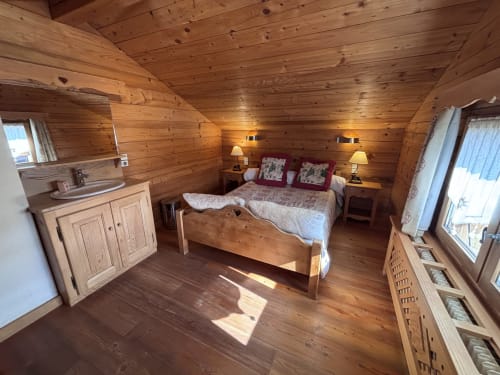 Cozy wooden chalet bedroom at Chez Francine with queen bed, ensuite bathroom, and warm pine interior in Notre Dame de