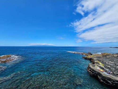 Crystal clear turquoise waters and rocky coastline at Playa La Arena, Santa Cruz de Tenerife, with blue sky