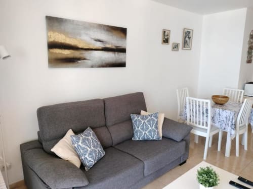 Modern living room with gray sofa and dining area at Olivia Playa La Arena apartment in Santa Cruz de Tenerife