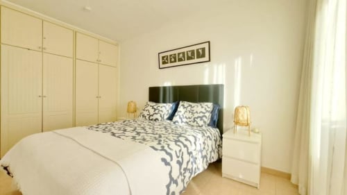 Bright bedroom in Olivia Playa La Arena apartment in Santa Cruz de Tenerife with green upholstered bed, cream wardrobes, and