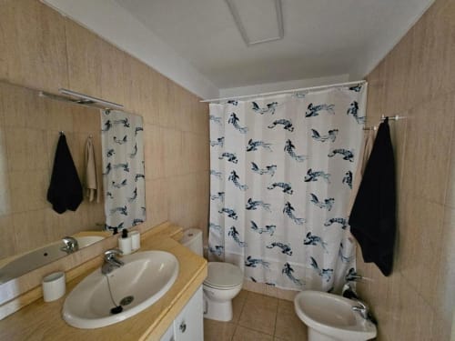 Modern bathroom in Tenerife apartment with sink, toilet, bathtub and nautical-themed shower curtain