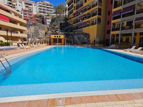 Bright blue swimming pool surrounded by colorful apartment buildings in Santa Cruz de Tenerife, Canary Islands