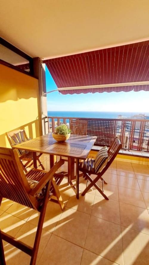 Sunny balcony with dining table overlooking ocean view in Santa Cruz de Tenerife apartment