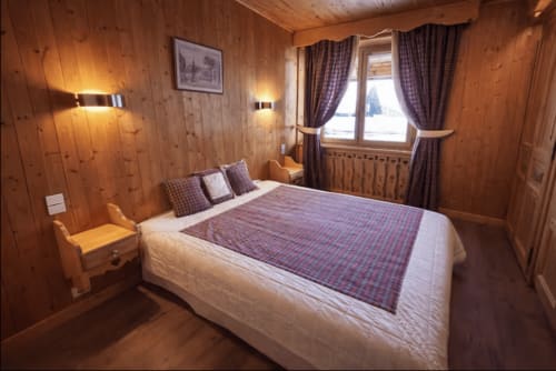 Cozy wooden chalet bedroom at Chez Francine with queen bed, mountain views, and alpine decor in Notre Dame de Bellecombe