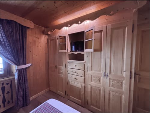 Cozy wooden chalet bedroom at Chez Francine with TV, storage, and alpine décor in Notre Dame de Bellecombe