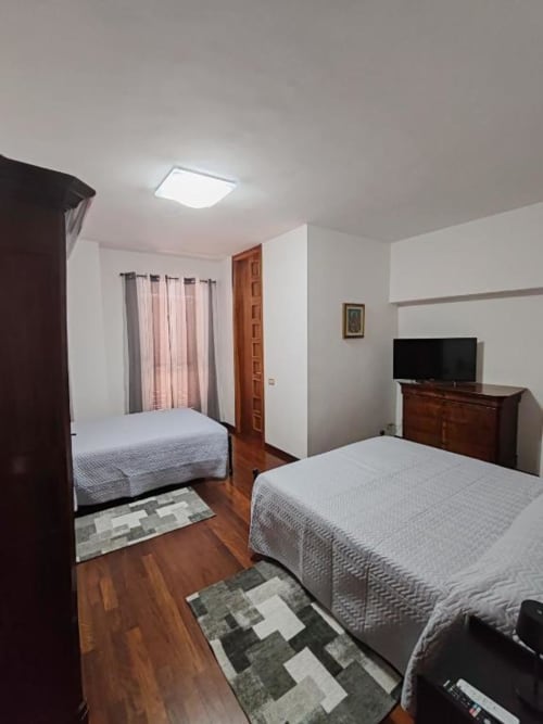 Triple Comfort room at Villa Andreina in Sarnano with two beds, wooden furniture, TV, and mountain views