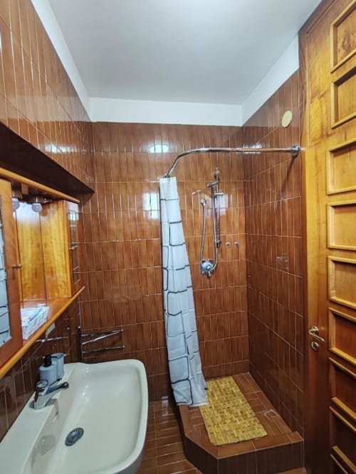 Modern bathroom with brown tile walls, white sink, and walk-in shower at Villa Andreina B&B in Sarnano, Italy