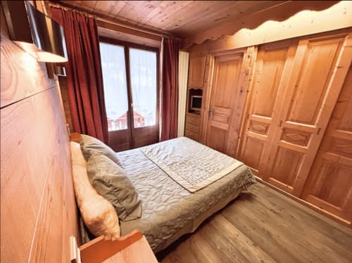 Cozy wooden bedroom at Chez Francine with double bed, wardrobe, and balcony view in Notre Dame de Bellecombe