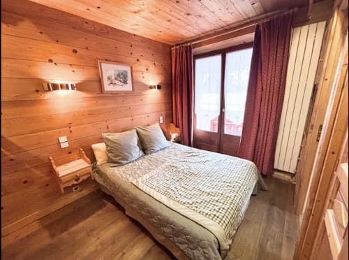 Chambre cosy en bois Chez Francine avec lit queen, rideaux bordeaux, vue sur balcon et paysage jardin