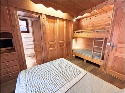Cozy wooden bedroom at Chez Francine with queen bed, bunk beds, and mountain view in Notre Dame de Bellecombe