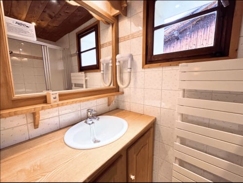 Bathroom at Chez Francine hotel in Notre Dame de Bellecombe with wooden vanity, white sink, and heated towel rack