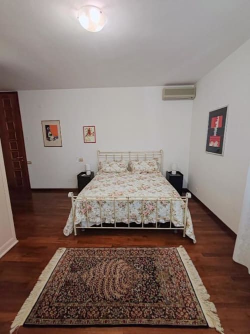Large double bedroom at Villa Andreina B&B in Sarnano with metal bed frame, patterned bedding, wooden floors, and mountain