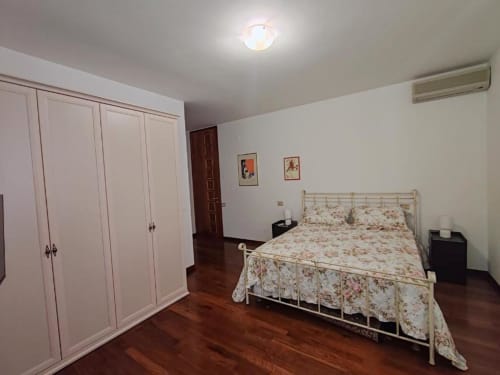 Spacious double bedroom at Villa Andreina B&B in Sarnano with floral bedding, white wardrobe, AC unit, and mountain views