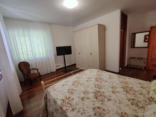 Large double bedroom at Villa Andreina B&B in Sarnano with floral bedding, white wardrobe, TV, and mountain views