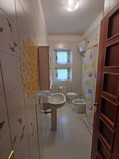 Modern bathroom at Villa Andreina in Sarnano with sink, bidet, toilet, and window with mountain views