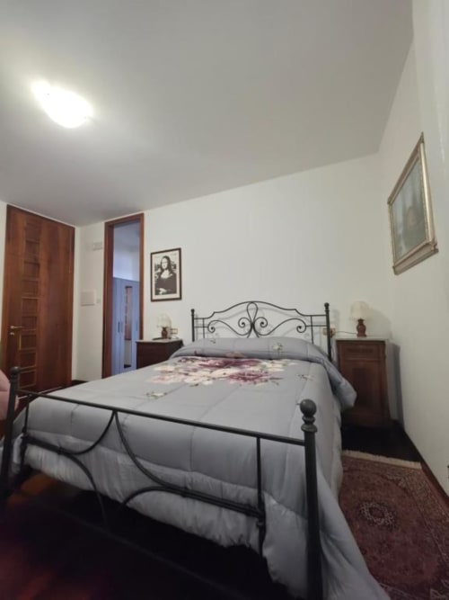 Elegant double bedroom at Villa Andreina in Sarnano with wrought iron bed, wooden nightstands, and garden view