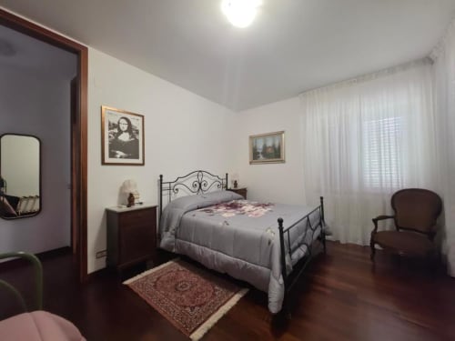 Villa Andreina Room 4 in Sarnano featuring double bed with wrought iron frame, dark wood flooring, and garden view windows