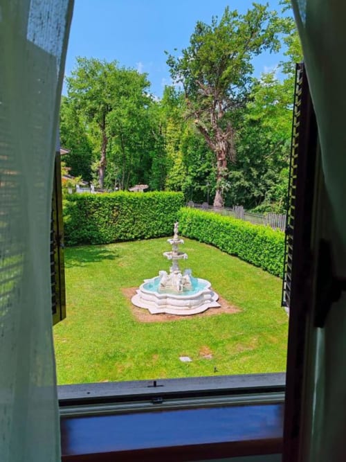 Villa Andreina garden view from Room 4, Sarnano: manicured lawn with fountain, hedges and tall trees