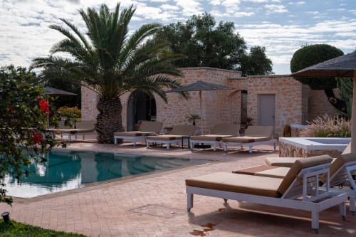 Pool view cottage at Domaine Belhazar in Essaouira with loungers, palm trees, and stone architecture