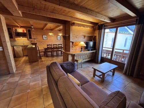 Spacious wood-paneled apartment living area with kitchen, sofa, TV, and mountain view balcony at Chez Marion, Notre Dame de