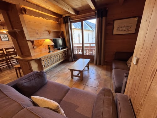Cozy wooden chalet apartment with fireplace, brown sofa, kitchenette and mountain view balcony in Notre Dame de Bellecombe