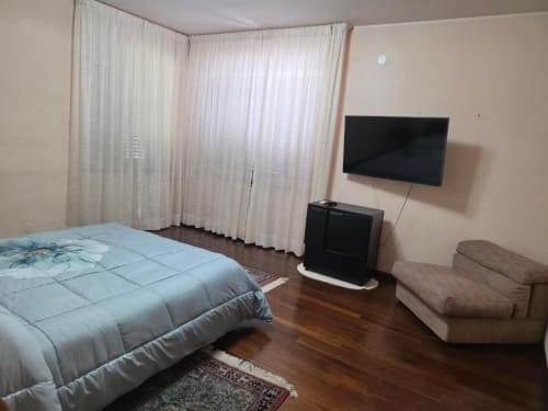 Room No.1 Suite at Villa Andreina in Sarnano with bed, flat screen TV, and garden view curtains