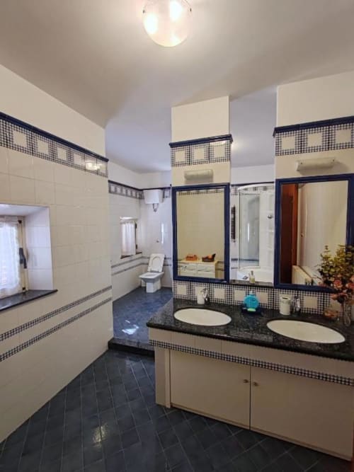 Modern bathroom with dual sinks, dark tile flooring, checkered accents, and shower at Villa Andreina B&B in Sarnano