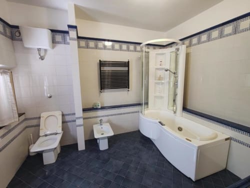 Modern bathroom in Suite Room No.1 at Villa Andreina B&B, Sarnano with white fixtures, black tile flooring, and chrome towel