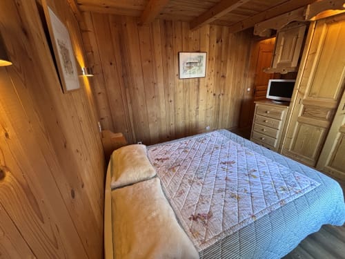 Cozy wooden bedroom with double bed, TV, and mountain views at Chez Marion in Notre Dame de Bellecombe